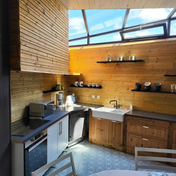 Cuisine moderne et lumineuse du Gîte L'Intemporelle, équipée avec électroménager, vaisselle et verrière en plafond.